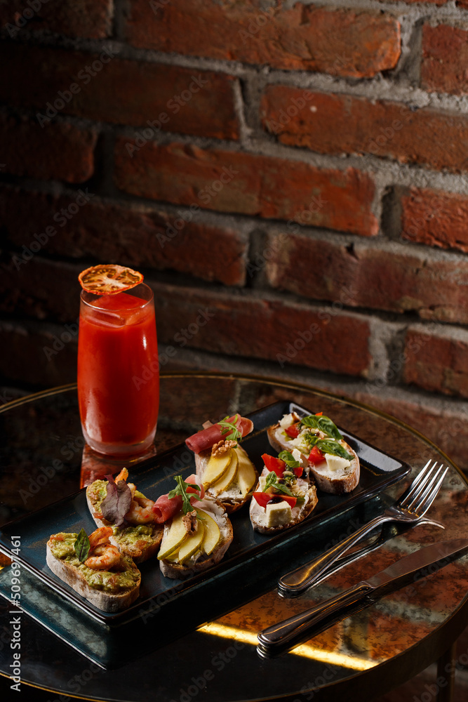 Bruschettas with vegetables. Start dishes with cherry tomatoes, avocado, cream cheese and shrimps. Food composition, tasty italian meal