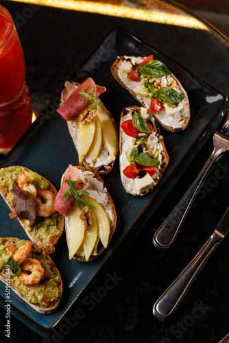 Obraz na płótnie Bruschettas with vegetables. Start dishes with cherry tomatoes, avocado, cream cheese and shrimps. Food composition, tasty italian meal w salonie