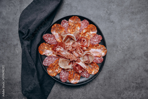 Different types of salami on a black platter, an appetizer for white wine or Prosecco in a restaurant aperitif meal photo