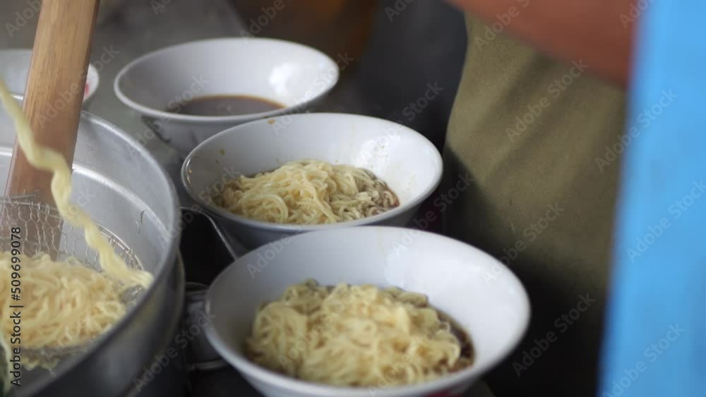 Making chicken noodles. View of a penjual mie ayam bakso or meatball chicken noodle seller who is making chicken noodles for the buyer. Selective focus. Making chicken noodles. View of a penjual mie ayam bakso or meatball chicken noodle seller who is making chicken noodles for the buyer. Selective focus.