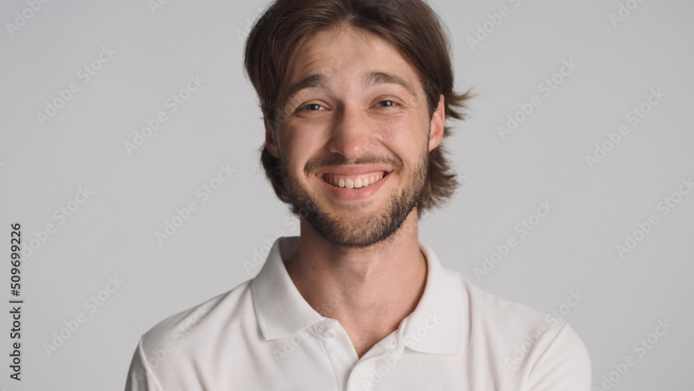 Portrait of smiling guy looking cheerful posing at camera over white background. Positive brunette man enjoying time with friends Portrait of smiling guy looking cheerful posing at camera over white background. Positive brunette man enjoying time with friends