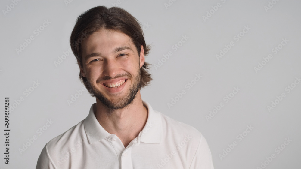 Beautiful guy sincerely smiling at camera over gray background. Positive man standing in studio Beautiful guy sincerely smiling at camera over gray background. Positive man standing in studio