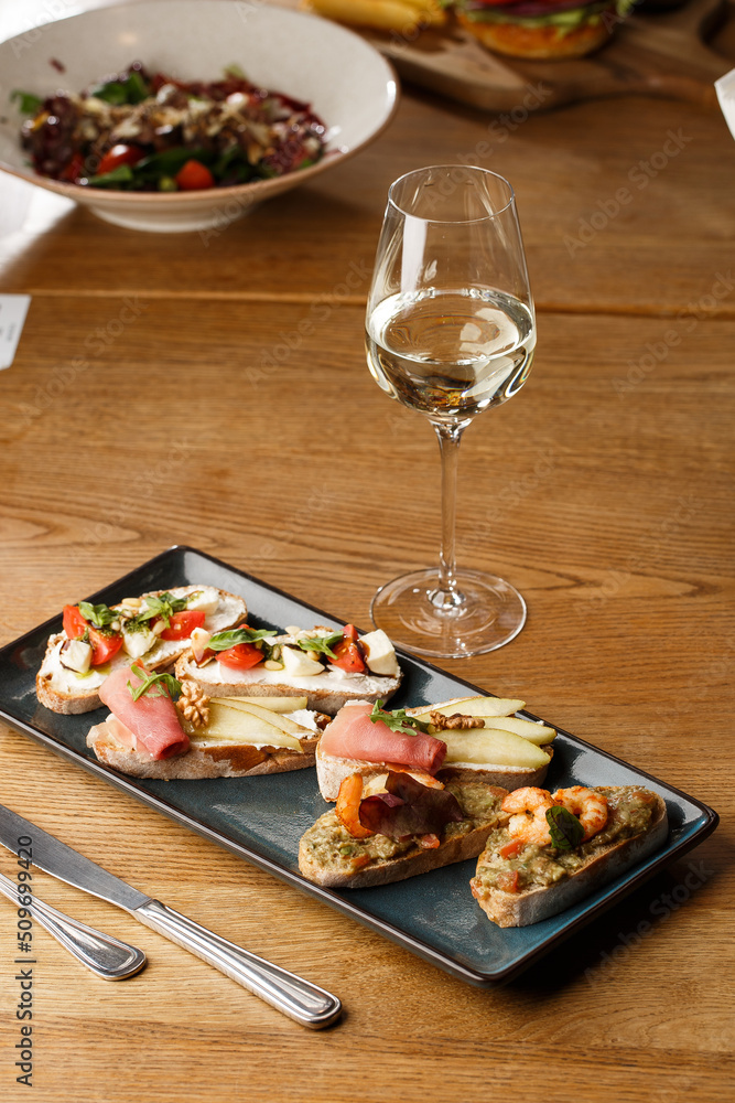 Bruschettas with vegetables. Start dishes with cherry tomatoes, avocado, cream cheese and shrimps. Food composition, tasty italian meal