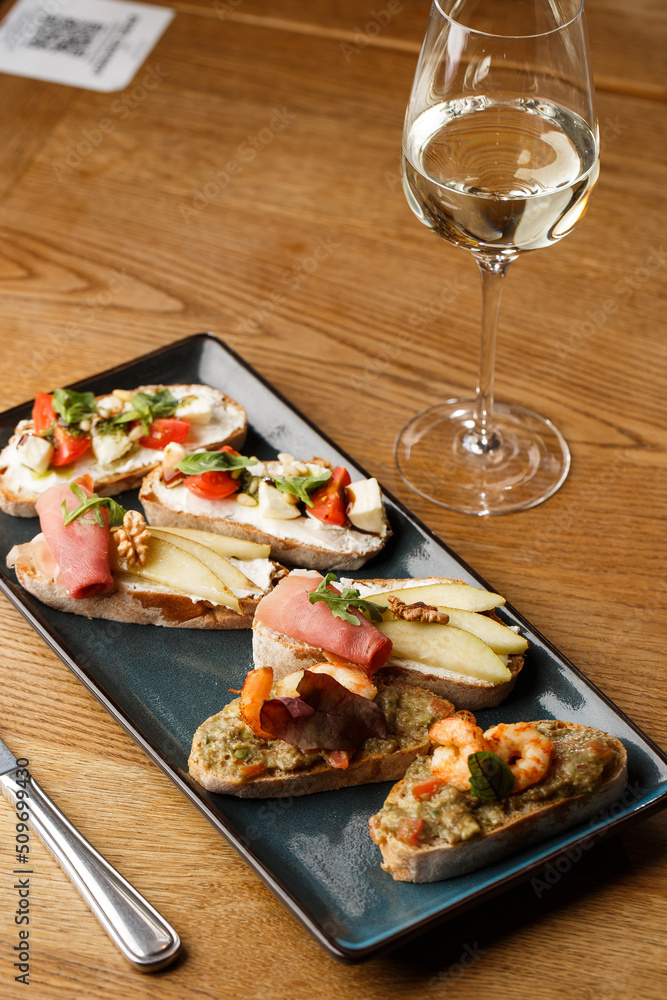 Bruschettas with vegetables. Start dishes with cherry tomatoes, avocado, cream cheese and shrimps. Food composition, tasty italian meal