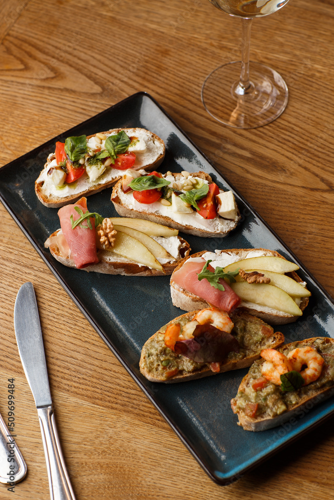 Bruschettas with vegetables. Start dishes with cherry tomatoes, avocado, cream cheese and shrimps. Food composition, tasty italian meal
