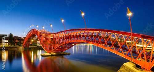 A bridge in the city at night. The bridge against the sky during the blue hour. The Python Bridge, Amsterdam, the Netherlands. Panoramic photography for design and background..