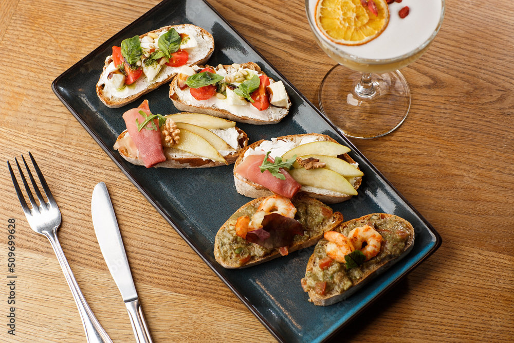Bruschettas with vegetables. Start dishes with cherry tomatoes, avocado, cream cheese and shrimps. Food composition, tasty italian meal