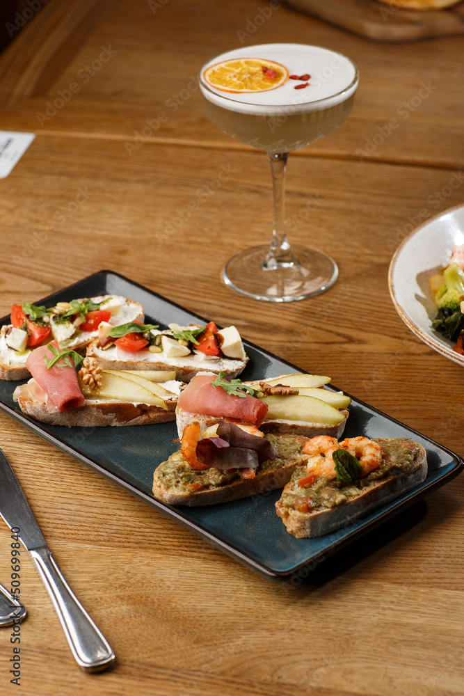 Bruschettas with vegetables. Start dishes with cherry tomatoes, avocado, cream cheese and shrimps. Food composition, tasty italian meal