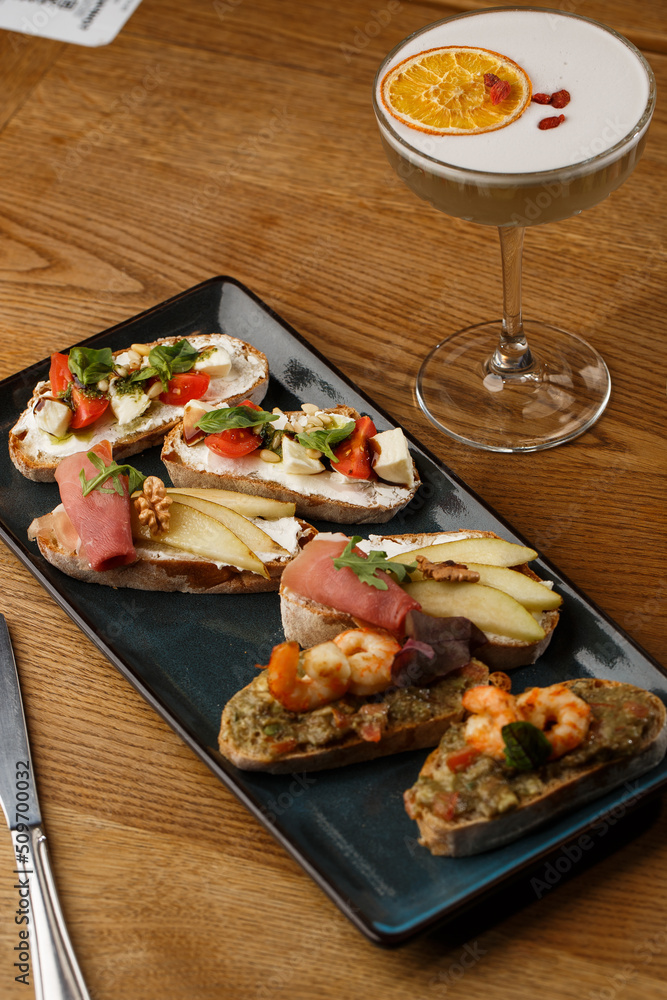 Bruschettas with vegetables. Start dishes with cherry tomatoes, avocado, cream cheese and shrimps. Food composition, tasty italian meal