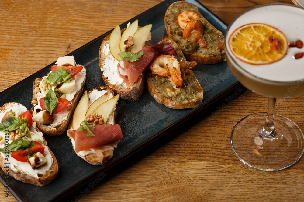 Bruschettas with vegetables. Start dishes with cherry tomatoes, avocado, cream cheese and shrimps. Food composition, tasty italian meal