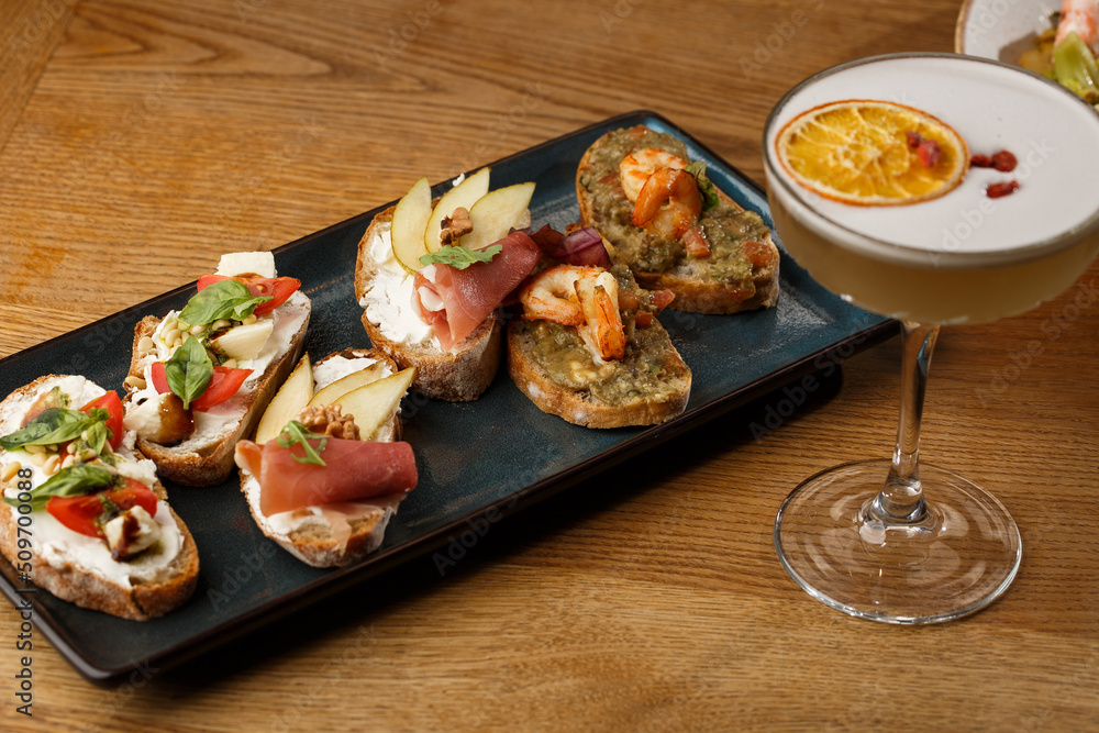 Bruschettas with vegetables. Start dishes with cherry tomatoes, avocado, cream cheese and shrimps. Food composition, tasty italian meal