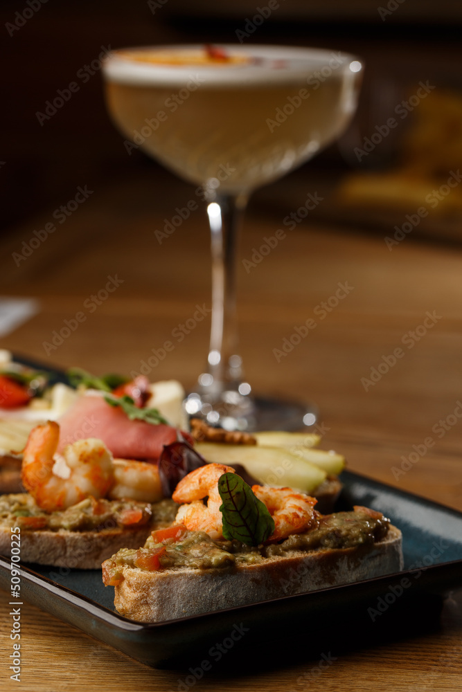 Bruschettas with vegetables. Start dishes with cherry tomatoes, avocado, cream cheese and shrimps. Food composition, tasty italian meal