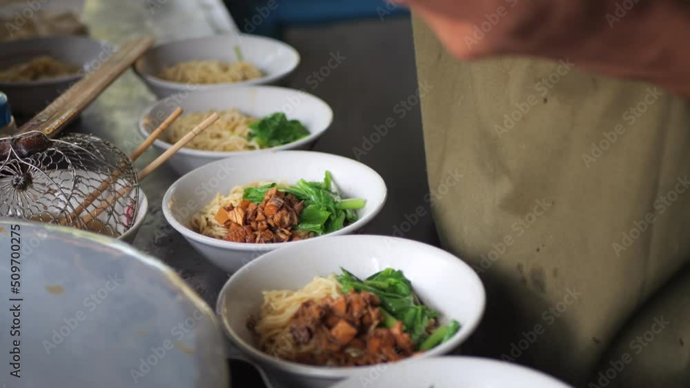 Making chicken noodles. View of a penjual mie ayam bakso or meatball chicken noodle seller who is making chicken noodles for the buyer. Selective focus. Making chicken noodles. View of a penjual mie ayam bakso or meatball chicken noodle seller who is making chicken noodles for the buyer. Selective focus.