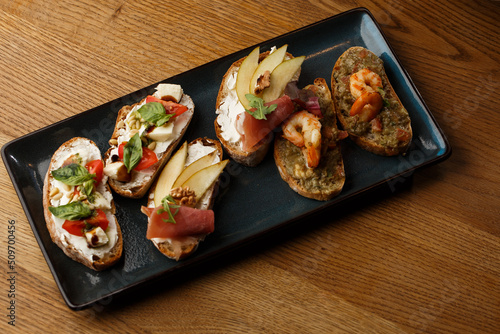 Obraz na płótnie Bruschettas with vegetables. Start dishes with cherry tomatoes, avocado, cream cheese and shrimps. Food composition, tasty italian meal w salonie