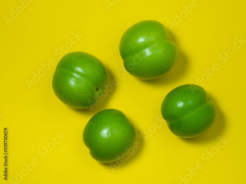Cherry plum fruits on a yellow background. Healthy green fruit. Southern fruit isolate.