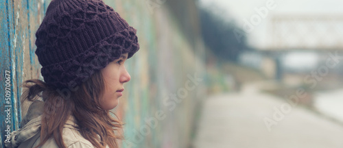 Sad teenage girl standing on the street in winter