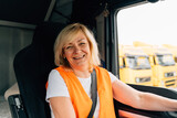 Mature woman truck driver steering wheel inside lorry cabin. Happy middle age female trucker portrait 