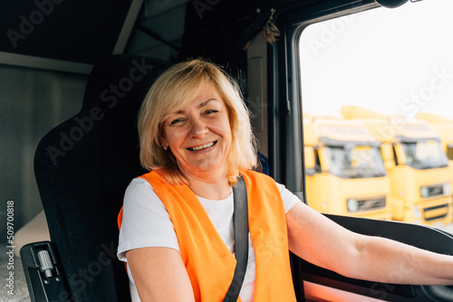 Mature woman truck driver steering wheel inside lorry cabin. Happy middle age female trucker portrait  photo
