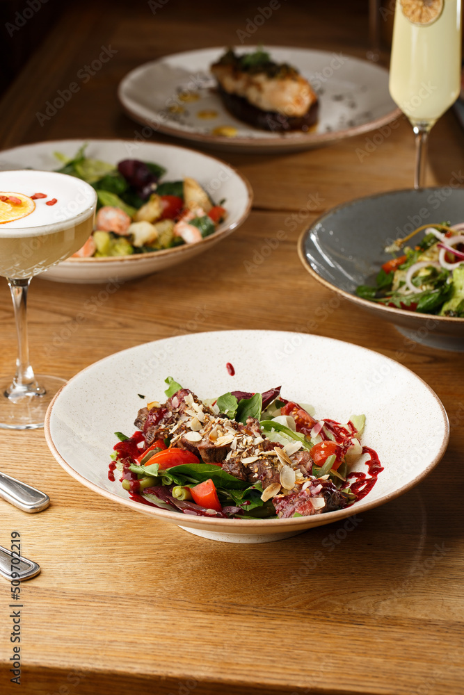 Salad with veal and tomatoes. Beef steak with raw vegetables mix side view. Grilled meat with garnish close-up. Delicious main course on table