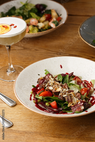 Obraz na płótnie Salad with veal and tomatoes. Beef steak with raw vegetables mix side view. Grilled meat with garnish close-up. Delicious main course on table w salonie