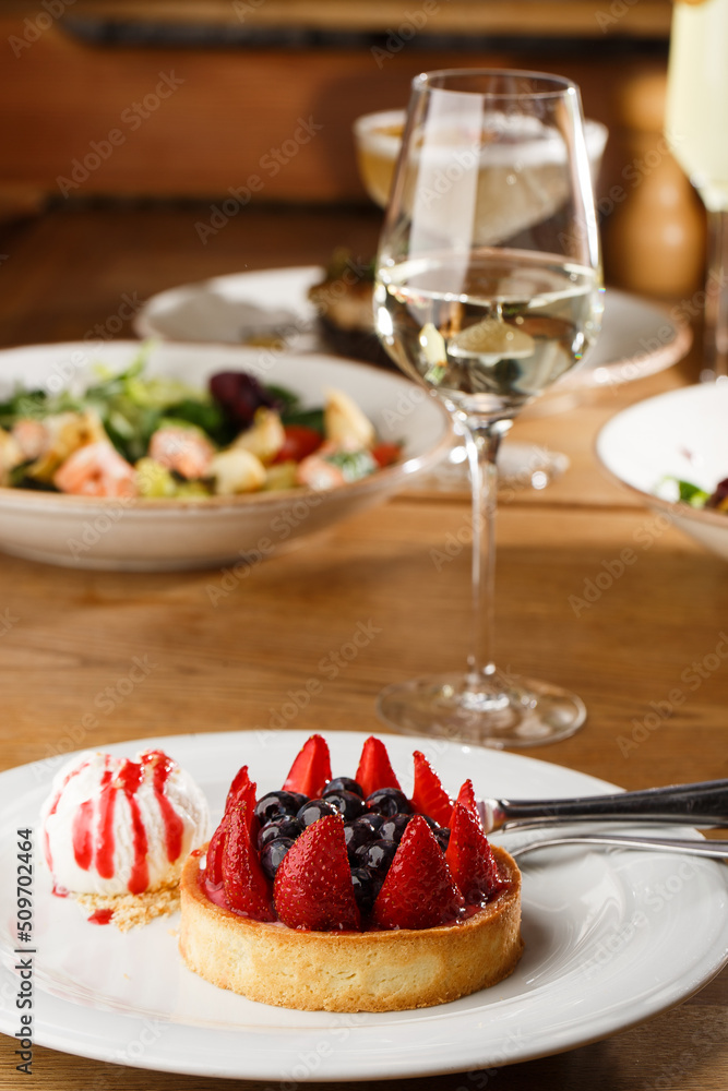 Berry tartlets with curd cream on a wooden background. Summer fruit baking. Tartlets with raspberries, blueberries and red currants. Served with ice cream.