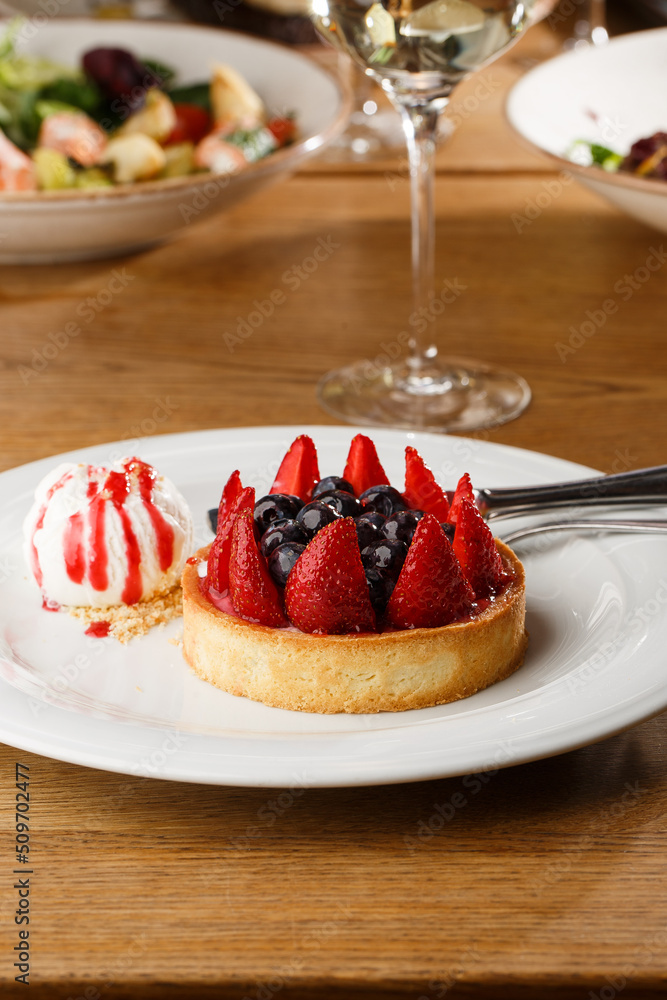 Berry tartlets with curd cream on a wooden background. Summer fruit baking. Tartlets with raspberries, blueberries and red currants. Served with ice cream.