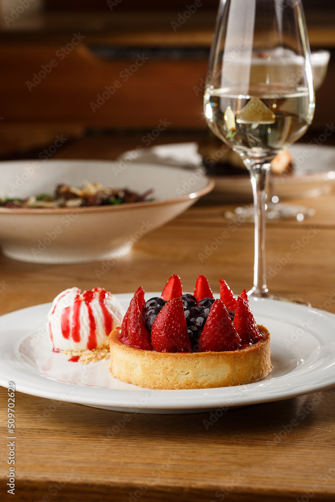 Berry tartlets with curd cream on a wooden background. Summer fruit baking. Tartlets with raspberries, blueberries and red currants. Served with ice cream.