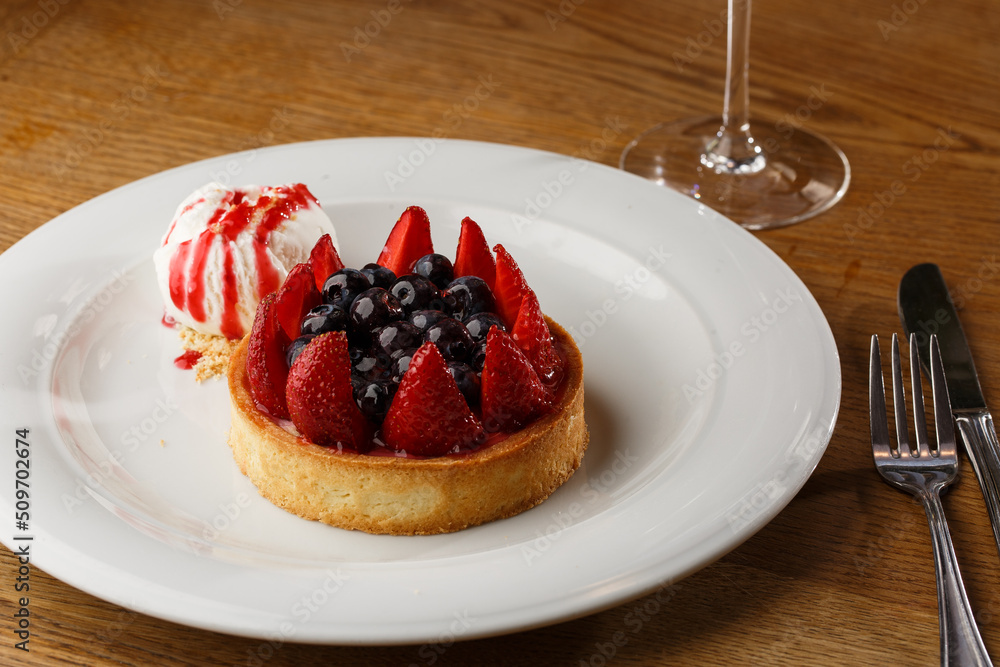 Berry tartlets with curd cream on a wooden background. Summer fruit baking. Tartlets with raspberries, blueberries and red currants. Served with ice cream.