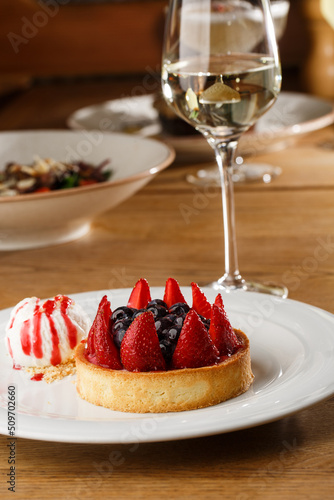 Obraz na płótnie Berry tartlets with curd cream on a wooden background. Summer fruit baking. Tartlets with raspberries, blueberries and red currants. Served with ice cream. w salonie
