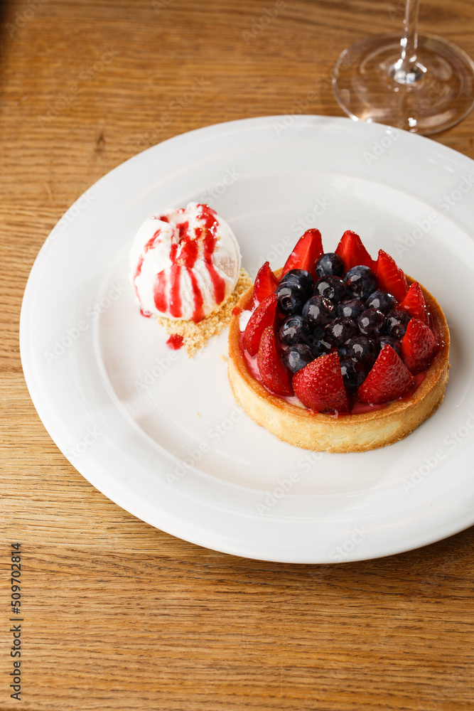 Berry tartlets with curd cream on a wooden background. Summer fruit baking. Tartlets with raspberries, blueberries and red currants. Served with ice cream.