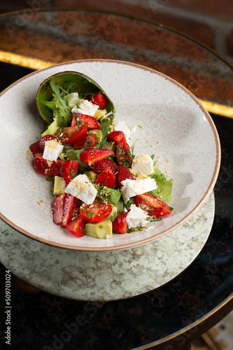Tasty and healthy salad with arugula, brie cheese, avocado, cherry tomatoes and strawberry. Top view. The flat lay. Banner