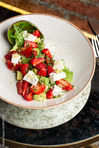 Tasty and healthy salad with arugula, brie cheese, avocado, cherry tomatoes and strawberry. Top view. The flat lay. Banner