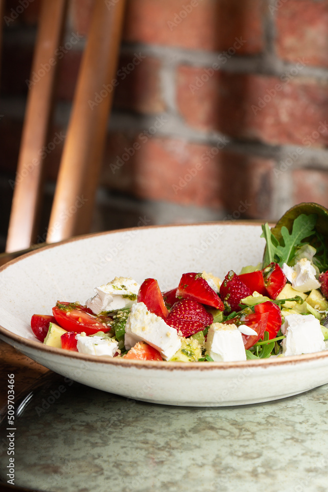 Tasty and healthy salad with arugula, brie cheese, avocado, cherry tomatoes and strawberry. Top view. The flat lay. Banner