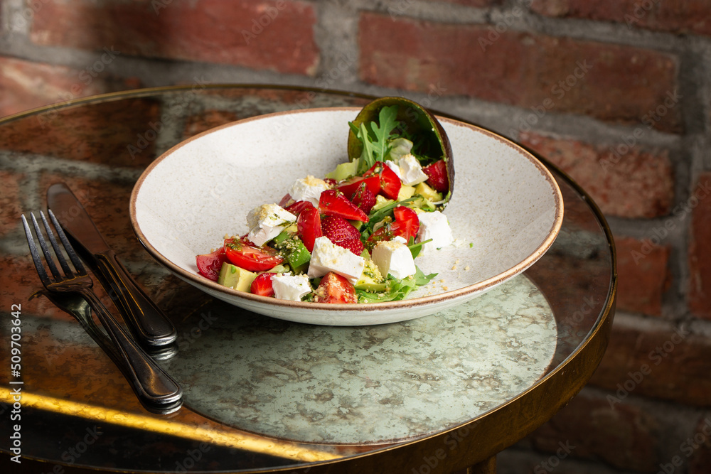 Tasty and healthy salad with arugula, brie cheese, avocado, cherry tomatoes and strawberry. Top view. The flat lay. Banner