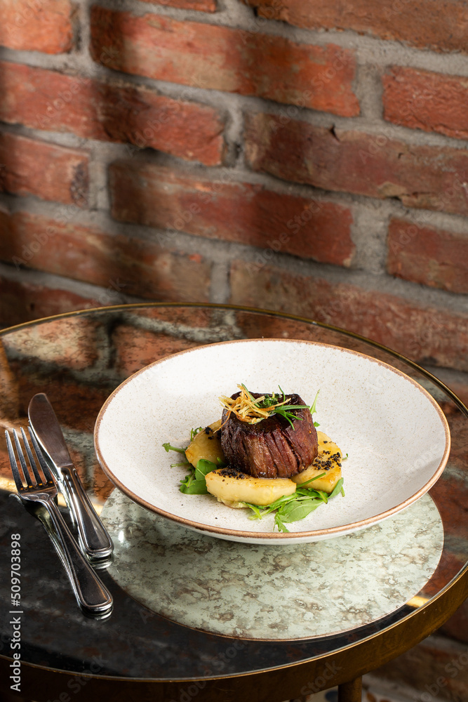 Grilled meat fillet steak medallion with green sauce, served with pear or apple. On dark background
