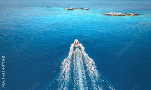 Fototapeta Naklejka Na Ścianę i Meble -  Aerial view of speed boat on blue sea at sunset in summer. Motorboat on sea bay, rocks in clear turquoise water. Tropical landscape with yacht, stones. Top view from drone. Travel in Oludeniz, Turkey