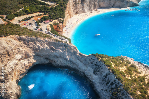 Aerial view of blue sea, mountains, white sandy beach at sunrise in summer. Porto Katsiki, Lefkada island, Greece. Beautiful landscape with sea coast, yacht, rocks, azure water, green forest. Top view photo