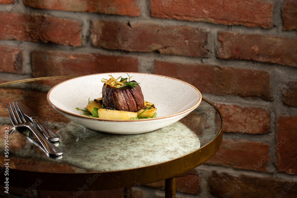 Grilled meat fillet steak medallion with green sauce, served with pear or apple. On dark background
