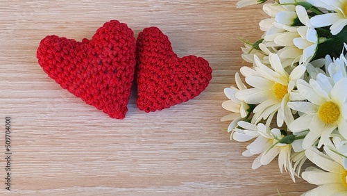 Crochet flowers and hearts on wooden background.