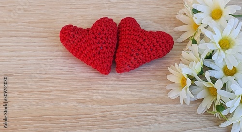 Crochet flowers and hearts on wooden background.