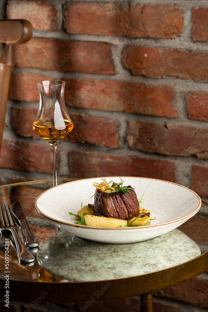 Grilled meat fillet steak medallion with green sauce, served with pear or apple. On dark background
