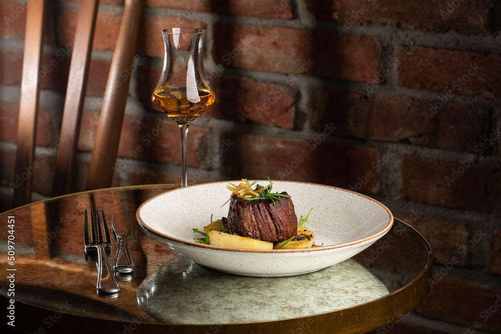 Grilled meat fillet steak medallion with green sauce, served with pear or apple. On dark background