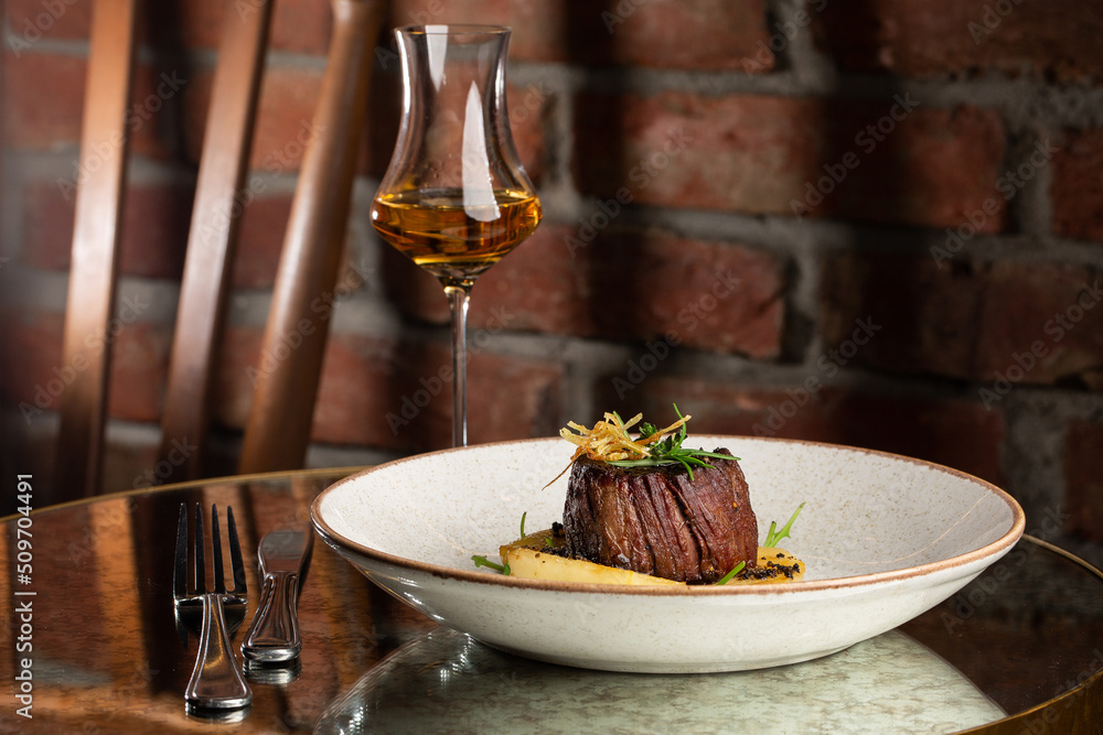Grilled meat fillet steak medallion with green sauce, served with pear or apple. On dark background