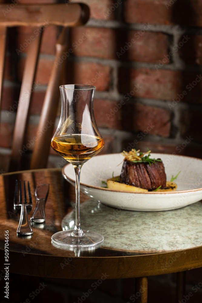 Grilled meat fillet steak medallion with green sauce, served with pear or apple. On dark background
