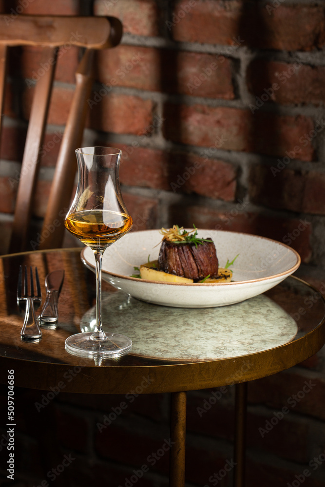 Grilled meat fillet steak medallion with green sauce, served with pear or apple. On dark background
