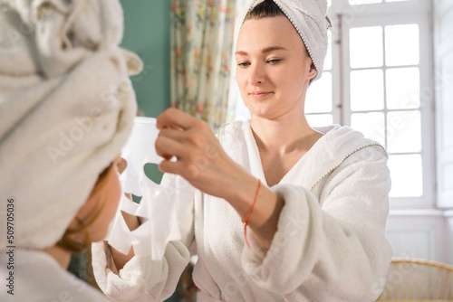 Little child girl sitting at the chair while her mother applying mask at her face