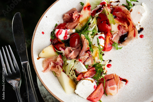 Obraz na płótnie Prosciutto crudo ham salad with mozzarella cheese and arugula on a plate. Bright background. Top view. Copy space w salonie