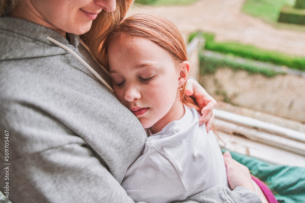 Little happy girl hugging mom, she leaning at female shoulder embracing her with both hands Little happy girl hugging mom, she leaning at female shoulder embracing her with both hands