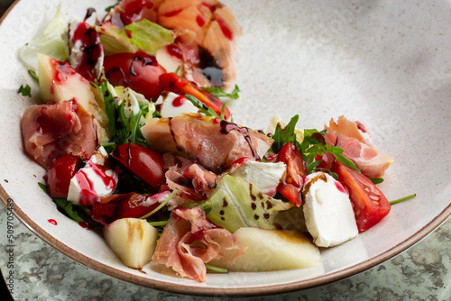 Obraz na płótnie Prosciutto crudo ham salad with mozzarella cheese and arugula on a plate. Bright background. Top view. Copy space w salonie