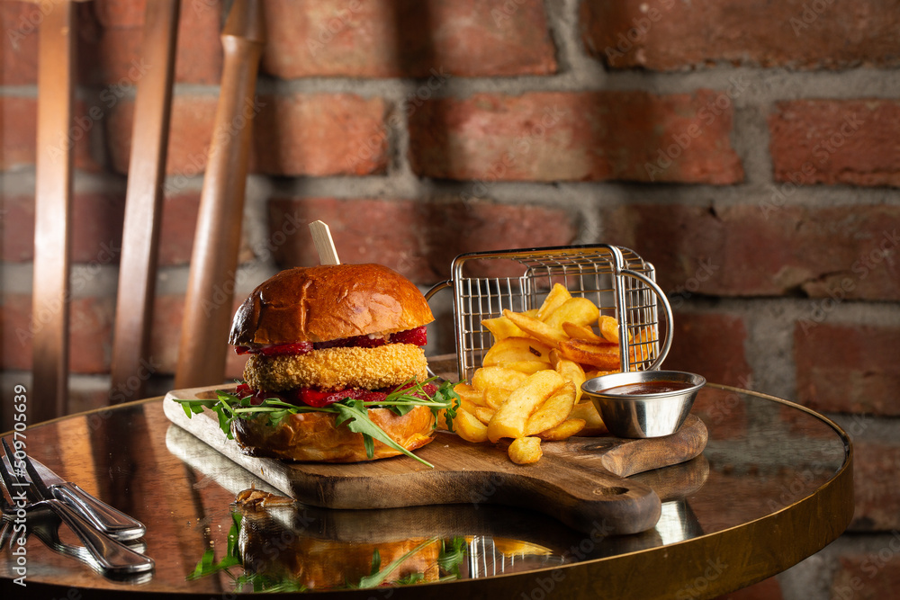 Big cheeseburger with french fries. Hamburger with beef patty onion, tomato, lettuce pickles, melted cheddar, mustards, tomato jam, mayo